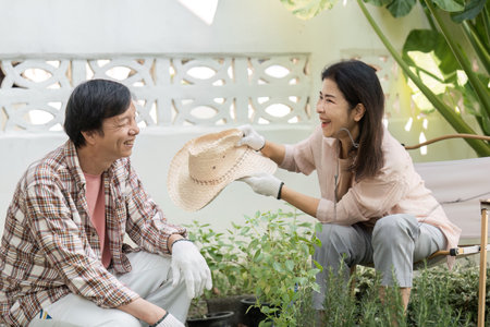 Diverse couple sharing a light moment while gardening, one playfully holds a hat.の写真素材