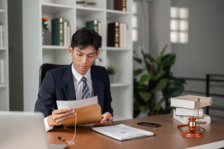 Young businessman reviewing important documents and preparing for tasks in a modern office setting.の写真素材