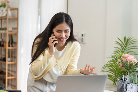 Smiling businesswoman on phone in home office, engaged in work and communication.の写真素材