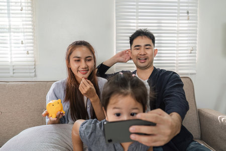 Family enjoying a video call together, sharing smiles and laughter at home.の写真素材