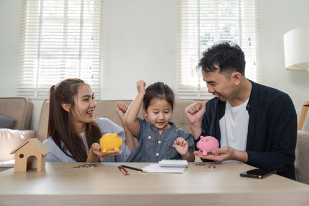 Happy family celebrating saving money with piggy banks and enthusiasmの写真素材