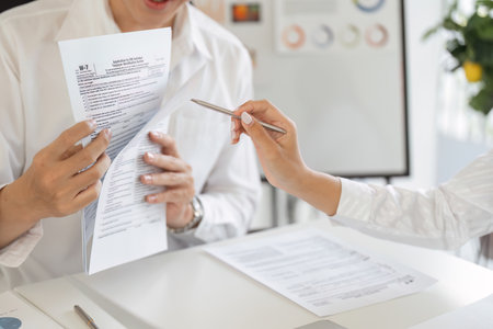 Tax professional reviewing W-2 form with a client, ensuring accurate tax filing and compliance.の写真素材