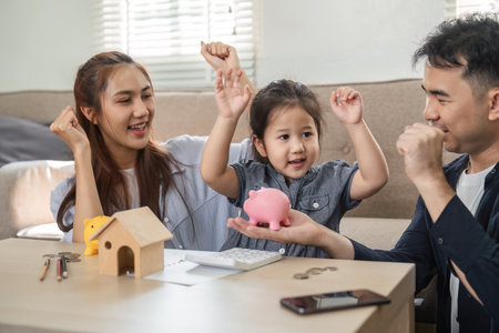 Family joyfully discussing saving strategies with piggy banksの写真素材