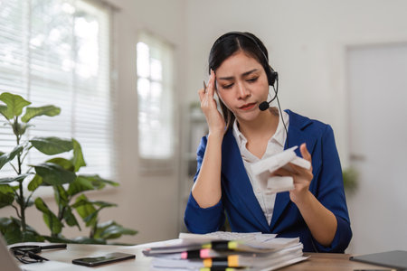 Concerned accountant handling financial difficulties while on a call, emphasizing the pressures of tax management.の写真素材