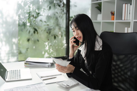 Accountant on the phone discussing financial matters while reviewing documents.の写真素材