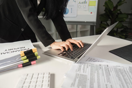 Businesswoman filing financial reports and managing tax documents on a laptop.