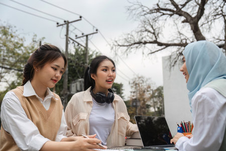 Diverse university students engaging in deep discussion while studying outdoors.の写真素材