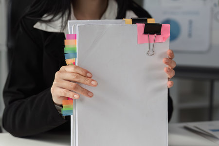 Accountant holding organized financial documents with colorful tabs for easy reference.の写真素材