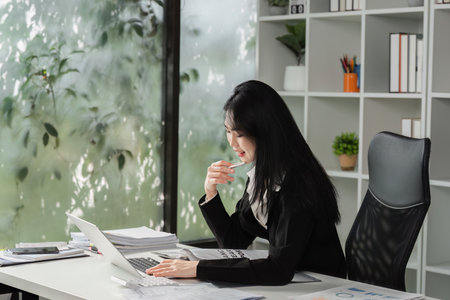 Accountant working on a laptop while engaging in a financial discussion over the phone.の写真素材