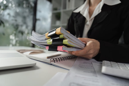 Businesswoman holding organized financial documents in officeの写真素材
