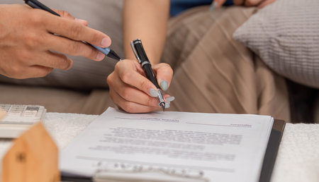 Signing for a new home. Close-up of hands signing paperwork in a real estate transaction.