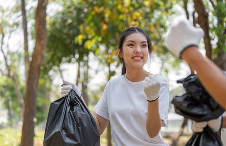Young woman participating in a community cleanup, promoting sustainability and environmental...