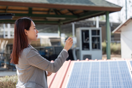Sustainable business initiative. Female professional examining solar panels for renewable energy project.の写真素材