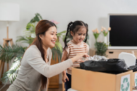Family and Environmental Awareness. A young girl learning the importance of recycling under her mothers guidance.の写真素材