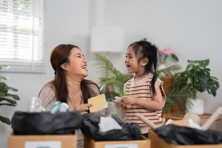 Sustainability and Family Bonding. A mother and daughter joyfully sorting recyclable materials together at home.の写真素材