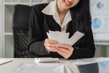 Financial organization and management. Woman smiling while sorting through tax documents.の写真素材