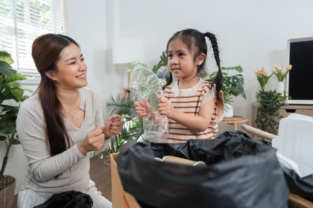 Joyful Recycling and Family Values. A mother and child excitedly sorting waste materials at home.の写真素材