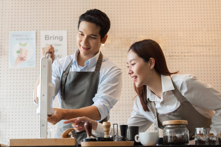 Training in Coffee Mastery. A barista demonstrating brewing techniques engaging a learner in a cafe environment.の写真素材