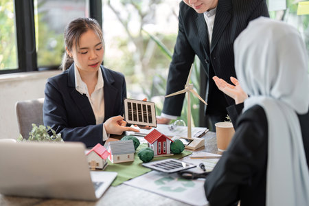 Collaboration and Green Solutions. Professionals showcasing renewable energy models in a design meeting.の写真素材