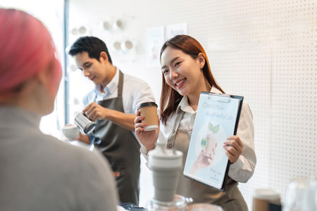 Sustainable Practices and Friendly Service. A barista showcases eco-friendly initiatives while serving coffee.の写真素材