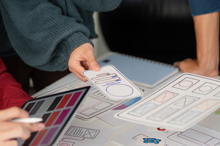 User Experience Design and Presentation. Designers showcasing mobile user interface layouts while discussing project ideas.の写真素材