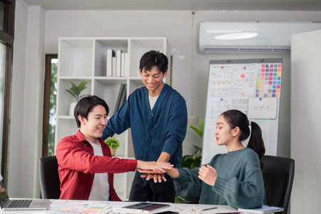 Creative Team Dynamics and Engagement. A group of young designers collaborating on ideas in a modern office environment.の写真素材