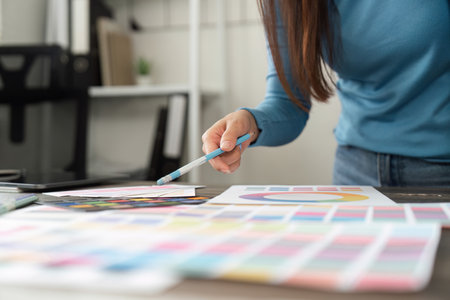 Design Process and Color Selection. A designer carefully evaluates color samples and palettes to enhance their project.の写真素材