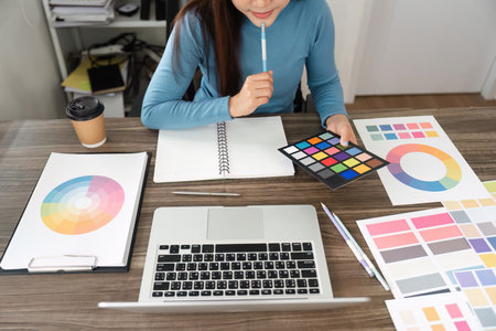 Creative Exploration and Color Palettes. A design enthusiast engaged in color palette selection using color charts.の写真素材