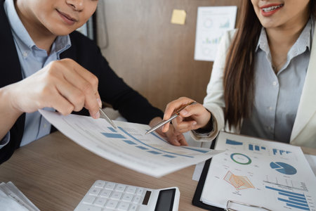 Business Analysis and Collaboration. Two professionals discussing financial reports to enhance decision-making in a corporate environment.の写真素材