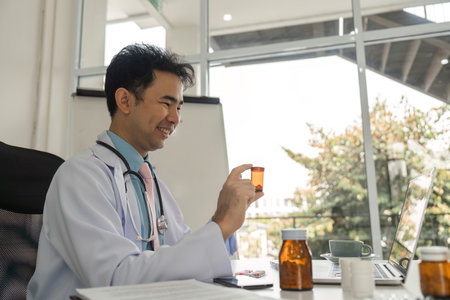 Telemedicine and Patient Consultation. A doctor smiles as he reviews medication during a virtual consultation.の写真素材