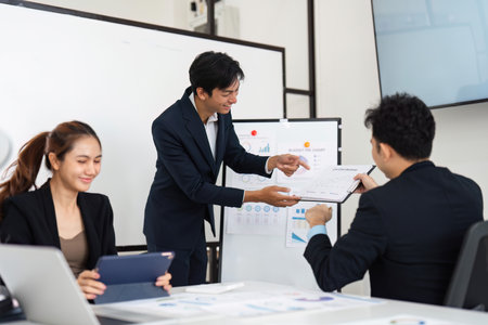 Creative Collaboration and Data Presentation. A young professional sharing analysis of budget details with colleagues during an interactive meeting.の写真素材