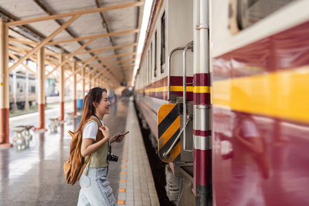 Connection and Anticipation. A young woman happily approaches the train while using her smartphone.