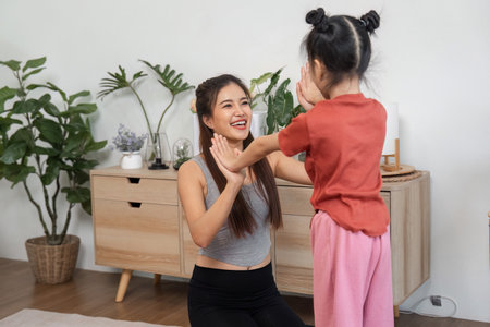 Mindfulness and Joy. A mother-daughter duo enjoying a playful yoga session, enhancing wellness and happiness.の写真素材