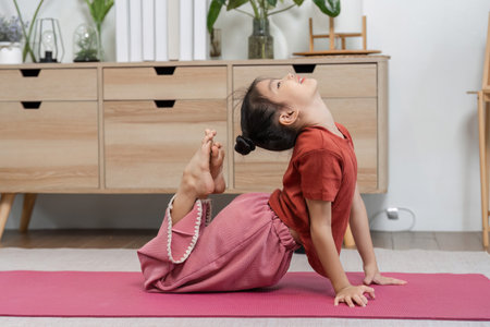 Yoga Practice and Flexibility. A child performs a yoga pose at home, showcasing flexibility and concentration.の写真素材