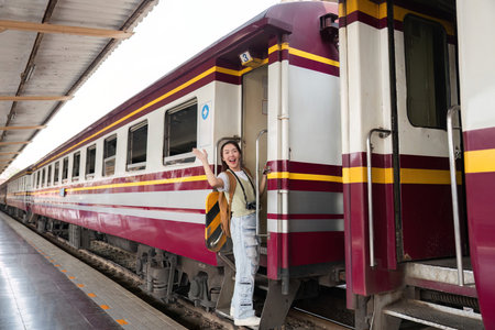Travel Excitement and Departure. A cheerful woman waving goodbye from the train, embracing her travel journey.の写真素材