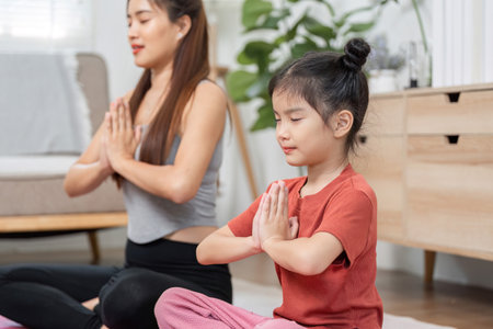 Meditation and Connection. A mother and daughter practice mindfulness together in a serene living room.の写真素材