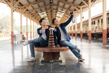 Travel and Exploration. Friends capturing joyful moments at a train station with their camera.の写真素材
