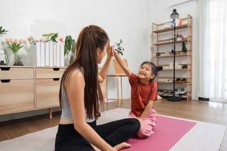 Exercise and Playful Moments. A mother and daughter sharing playful high-fives during a fun workout at home.の写真素材