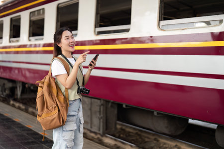 Joy and Anticipation of Travel. A woman with a camera smiling and pointing, excited for her train journey.の写真素材
