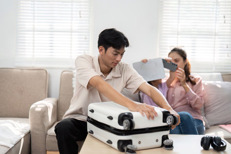 Family Dedication and Planning. A father carefully packs a suitcase while the family enjoys quality...
