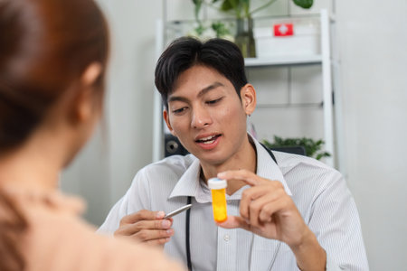 Patient Consultation and Medication Guidance. Doctor engaging with a patient while presenting a prescription bottle.の写真素材