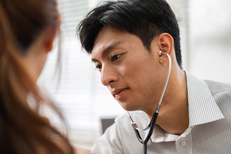 Healthcare Consultation and Patient Engagement. A doctor using a stethoscope to listen to a patient's heart during a medical checkup.の写真素材