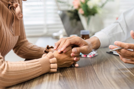 Compassionate Health Consultation and Emotional Support. Doctor holding a patient's hand during a consultation.の写真素材