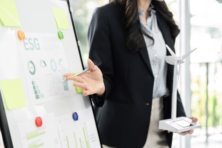 ESG Meetings and Renewable Models. Team discussing eco-friendly strategies and showcasing wind energy models for ESG performance.の写真素材