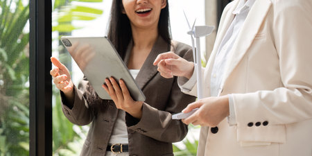Collaboration and Sustainability. Two businesswomen discussing renewable energy solutions with a tablet in hand.の写真素材