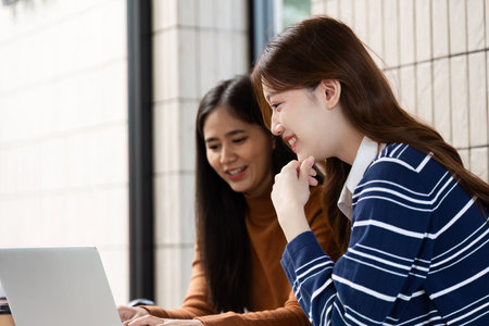 Digital Learning and Collaboration. Two students enjoy digital resources while studying together at...