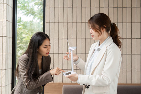 Sustainability and Innovation. Two professionals discussing renewable energy solutions in a modern office setting.の写真素材