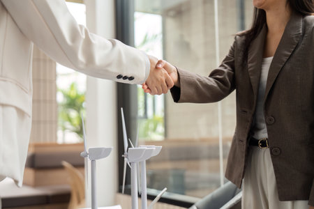 Agreement and Sustainability. Businesswomen emphasizing eco-friendly practices during a handshake.
