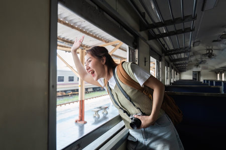 Dynamic Travel and Enthusiasm. A woman waves goodbye from the window of a train, embracing the joy of travel.の写真素材