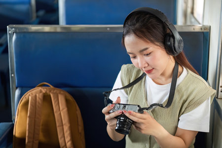 Photography and Exploration. A young woman capturing moments with her camera on a train.の写真素材